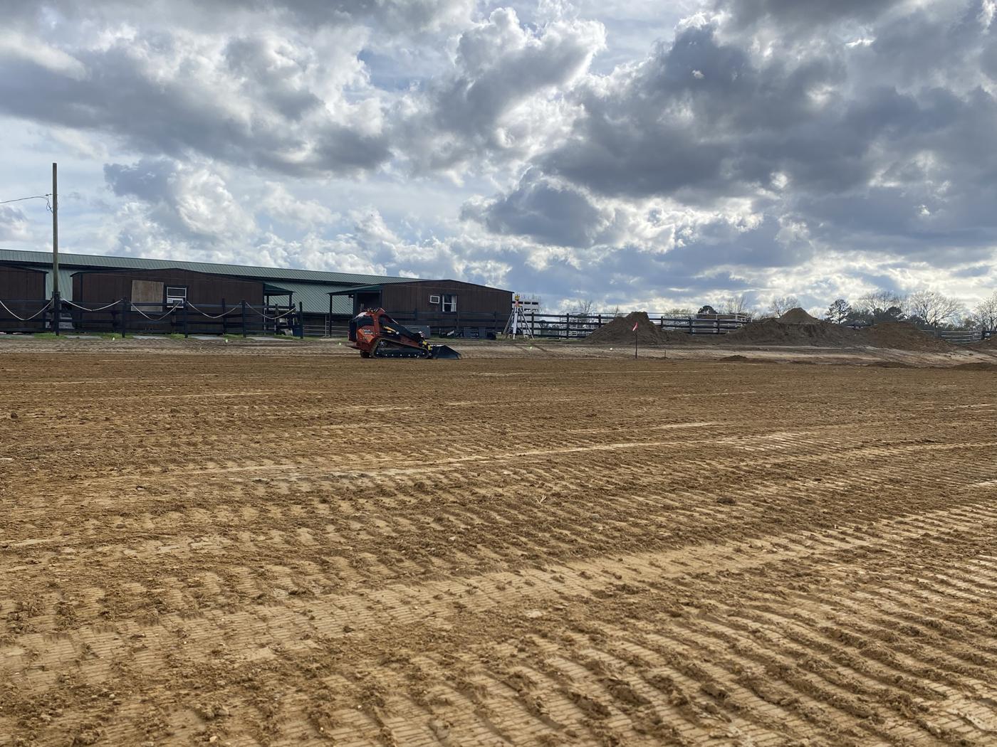 Freshly graded dirt beside a horse barn